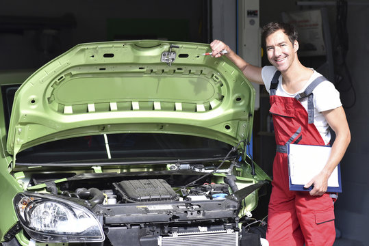Car mechanic examining accident damaged car before repair
