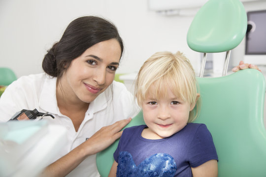 Dentist and smiling girl in dentist's chair