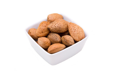 Almonds in shell of square bowl on a white background