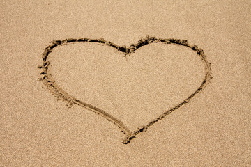 heart symbol drawn in the sand on a beach with wave. Valentine's