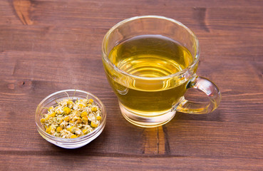 Cup of chamomile tea with flowers on wooden table