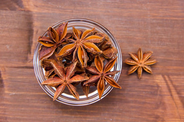 Star anise on bowl on wooden table seen from above