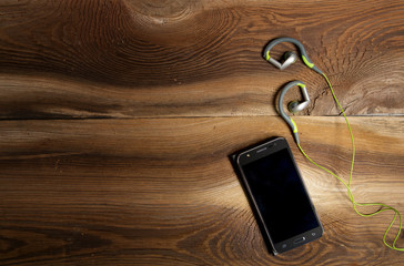 Telefon i słuchawki na drewnianym tle