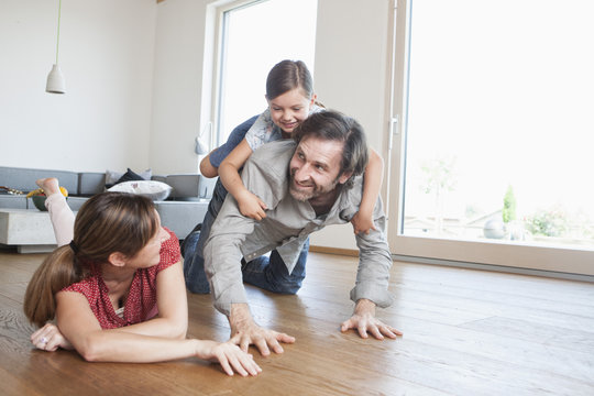 Happy family lying on floor, playing with daughter