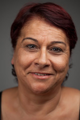 Portrait of smiling cheerful middle-aged woman isolated on gray