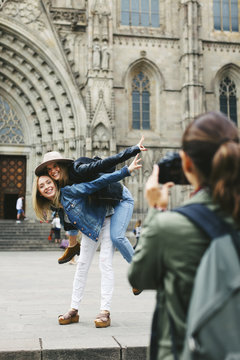 Spain, Barcelona, woman taking picture of two playful young women in the city in the city