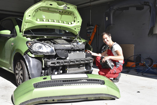 Car mechanic examining accident damaged car before repair