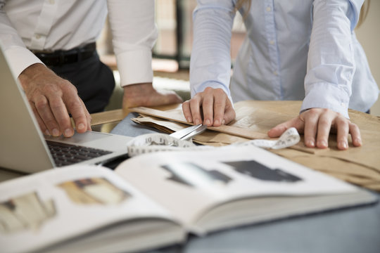 Mature man and young woman working together at tailoring shop
