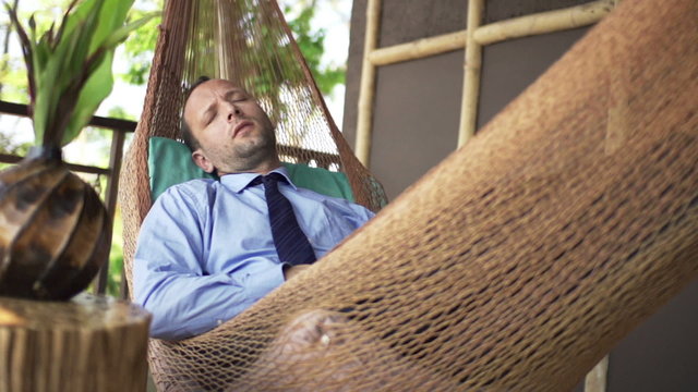 Young businessman sleeping on hammock on terrace, super slow motion 240fps

