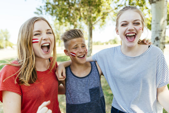 Austria, three teenagers with national colors painted on their cheeks celebrating together