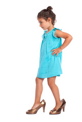 Cute little girl trying to walk with big high heel shoes