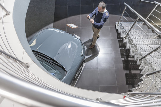 Man taking picture of new car in showroom