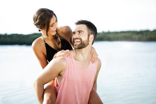 Germany, Haltern, man giving his girlfriend a piggy back in front of Silbersee