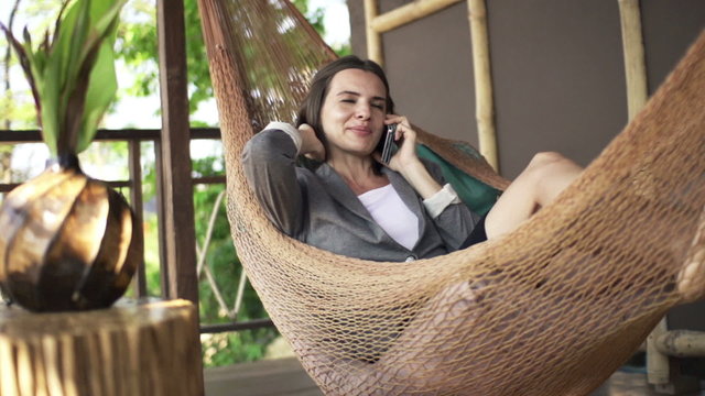 Young, pretty businesswoman talking on cellphone on hammock

