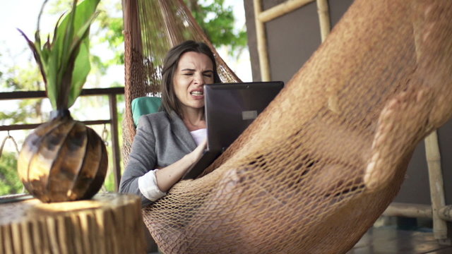 Angry businesswoman with laptop lying on hammock, super slow motion 240fps
