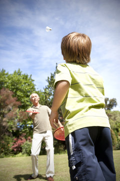 Little boy playing badminton with his grandfather
