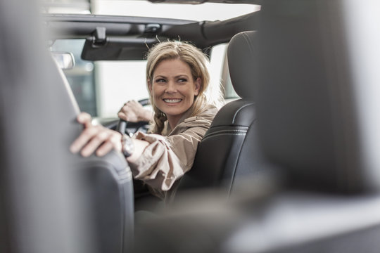 Smiling woman in car driving back out