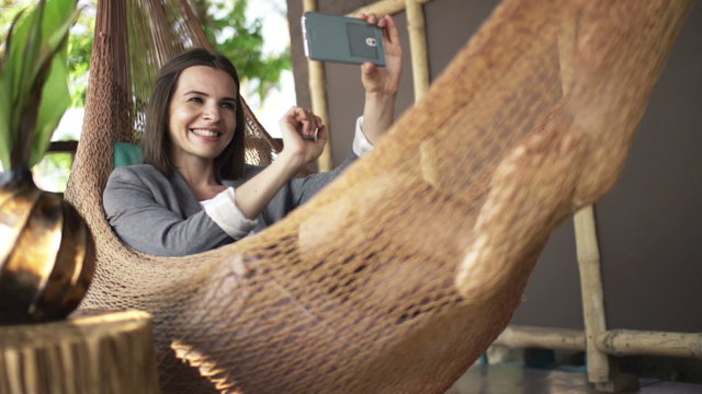 Businesswoman taking selfie photo with smartphone on hammock, super slow motion 240fps
