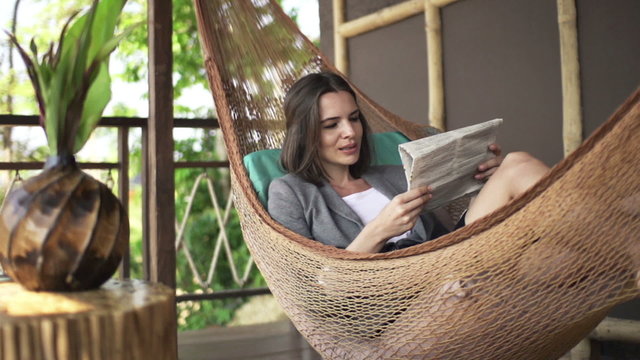 Businesswoman reading newspaper on hammock on terrace, super slow motion 240fps
