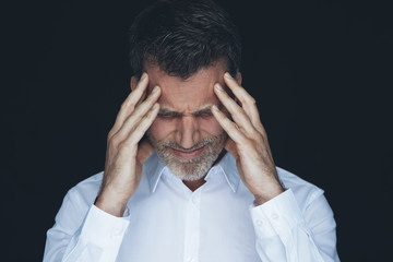 Portrait of man with hands on his forehead in front of black background