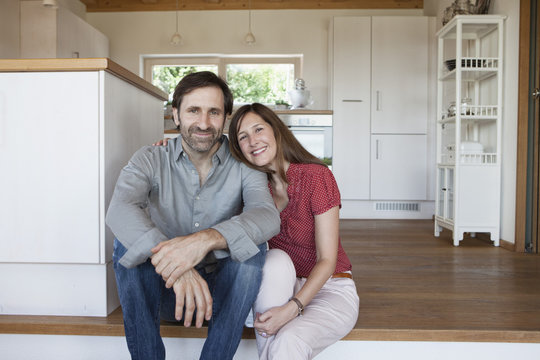 Mature couple sitting on floor, front view