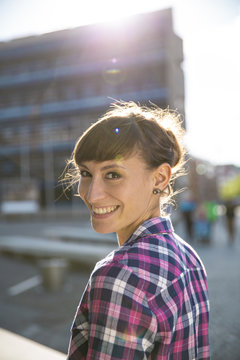 Germany, Berlin, portrait of smiling young woman at twilight