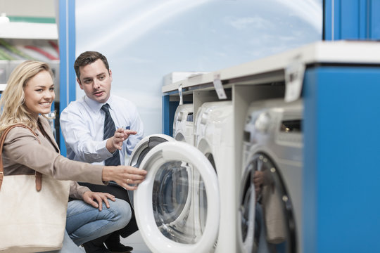 Shop assistant explaining washing machine to customer
