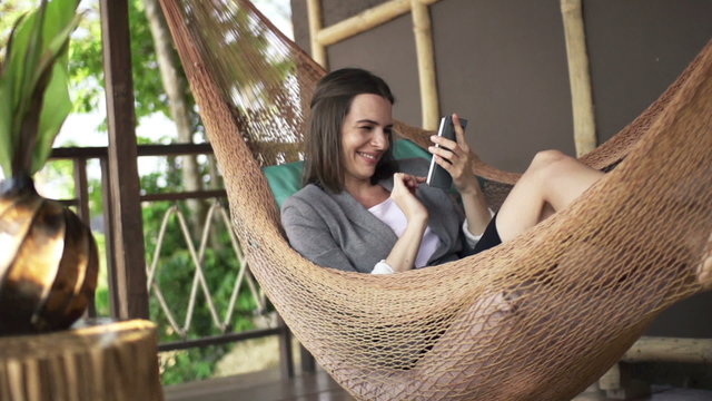 Happy businesswoman with smartphone lying on hammock, super slow motion 240fps
