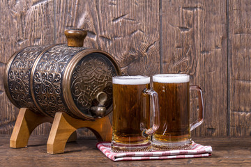 Copper forged barrel and a two mug of beer on a old table