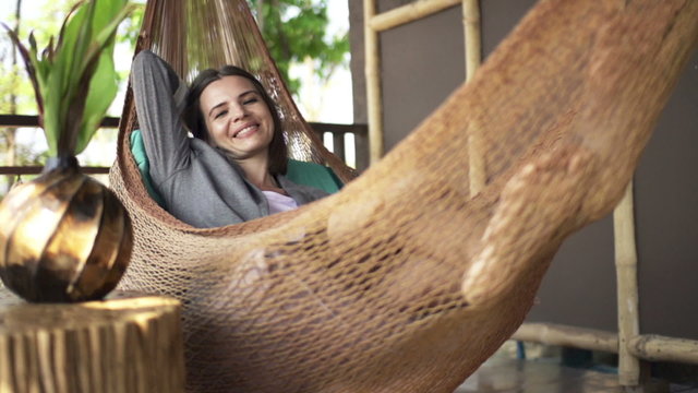 Portrait of happy businesswoman relaxing on hammock on terrace
