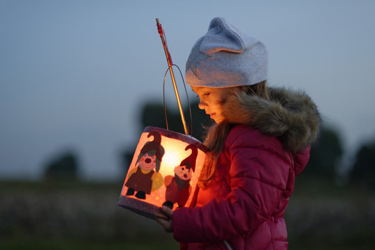 Little girl with self-made paper lantern in the evening