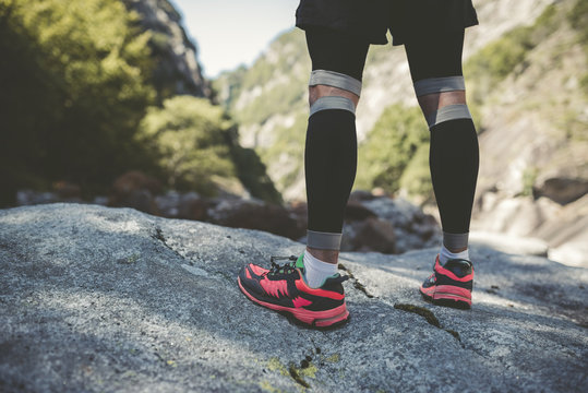 Ultra runner in mountains standing on rock