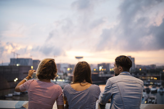 Spain, Barcelona, back view of three friends looking at view from a bridge