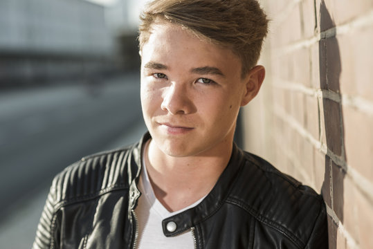 Portrait of young man leaning against brick wall