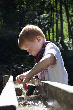 Boy playing at water runlet