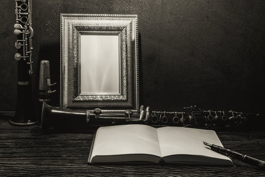 Still life of picture frame on wooden table with clarinet