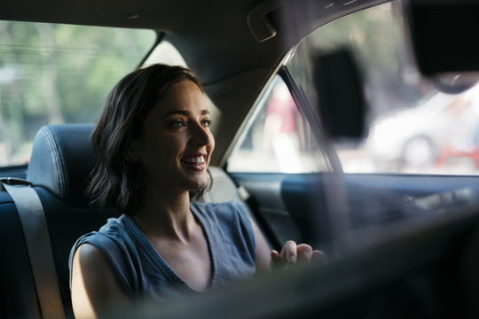 Portrait of happy young woman sitting inside of a cab