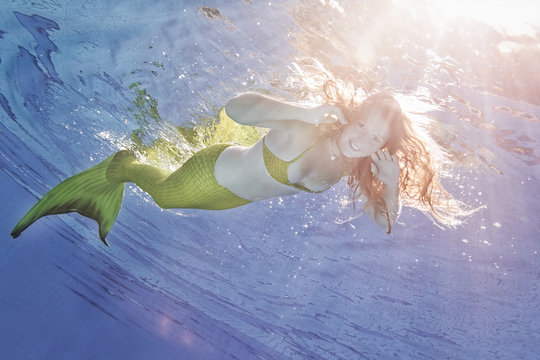 Young woman in the disguise of Arielle, the little mermaid, underwater