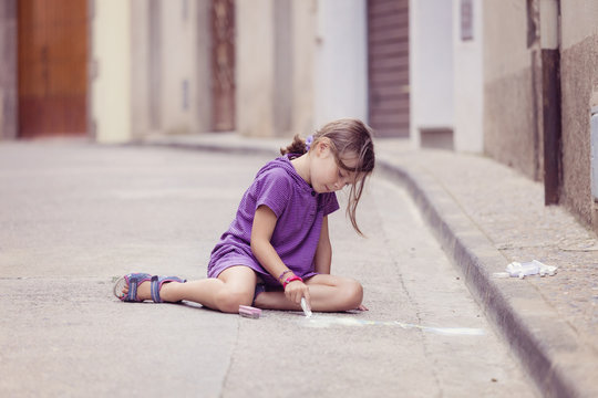 Little girl drawing with crayon on the street