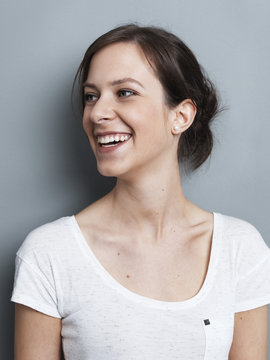 Portrait of smiling brunette woman in front of gray background