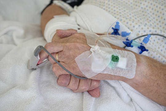 Hands of senior man with cannulae and band-aid being in intensive care