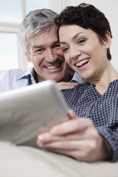 Germany, Bavaria, Munich, Couple using digital tablet at home, smiling