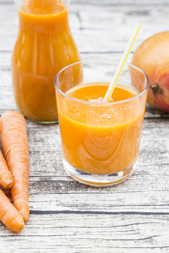 Glass And Bottle Of Mango Carrot Smoothie On Grey Wood