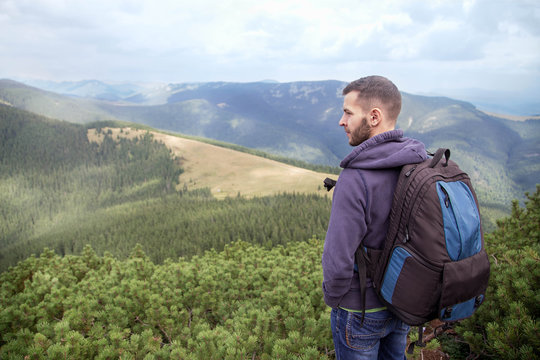 Outdoor portrait of Young man hiking 

on the mountains,smiling happy 

portrait of tourist male. Travel bag, 

caucasian Male hiker walking in forest