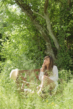 Young woman smoking on wooden bench in a garden