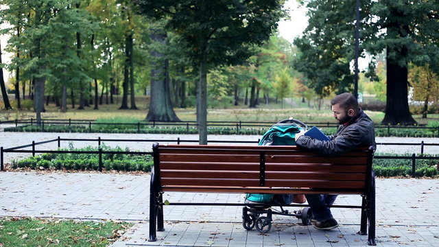 Father with stroller writing notes in notebook in the park

