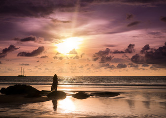 Naklejka na ściany i meble Young woman looking sunset on the beach in Phuket Thailand