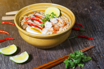 Thai food style noodle, tom yum kung on wood background