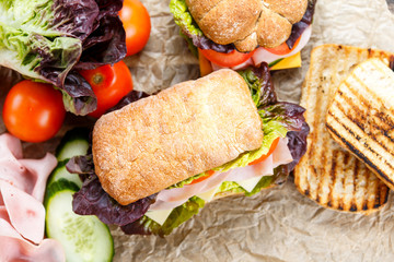 Grilled Sandwich with lettuce, slices of fresh tomatoes, cucumber, red onion, salami, ham and cheese.