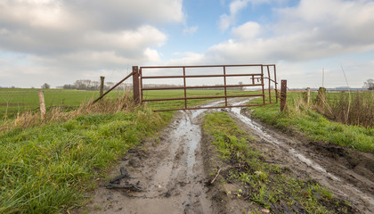 Fototapeta na wymiar Rusty gate in muddy farmland